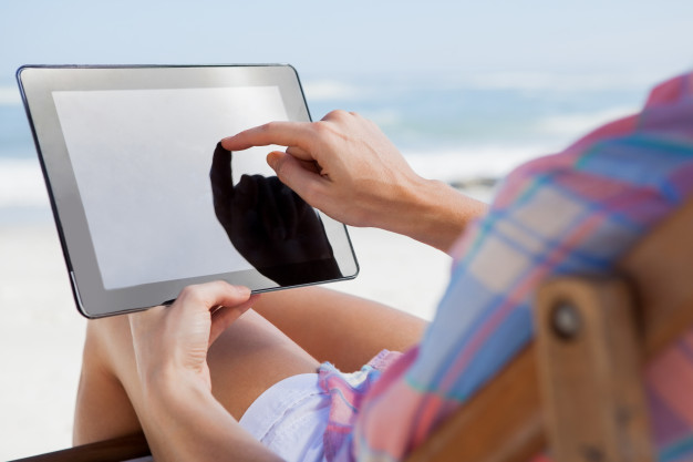 woman-sitting-on-beach-in-deck-chair-using-tablet-pc_13339-564171jpg