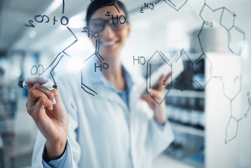 happy female scientist designing molecules on a transparent board